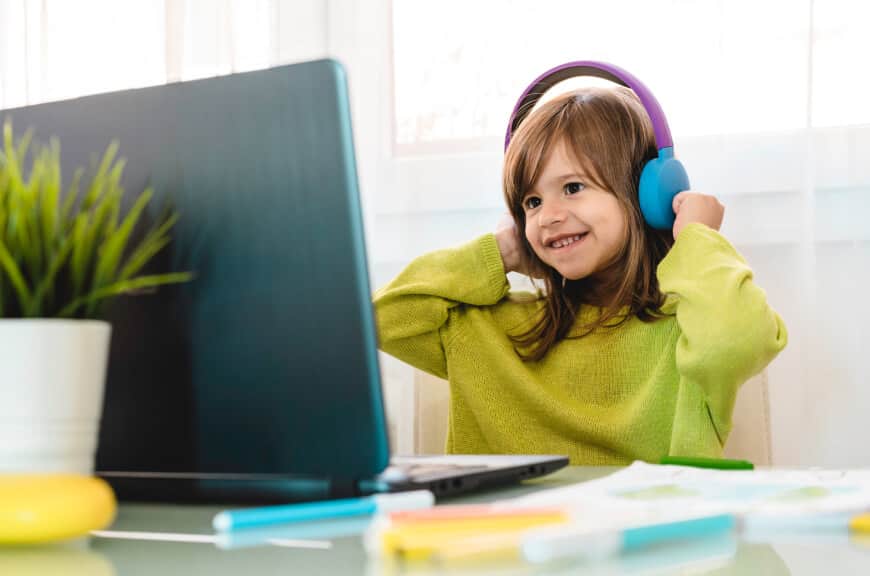 young female listening on headphones while on laptop