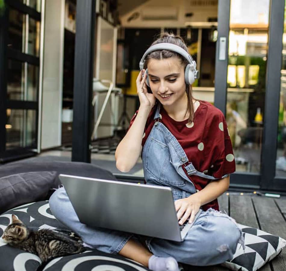teenage girl on computer with headphones red shirt