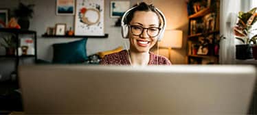 Young woman teaching online from her living room. Young woman wearing headphones while having a video call and looking at the camera